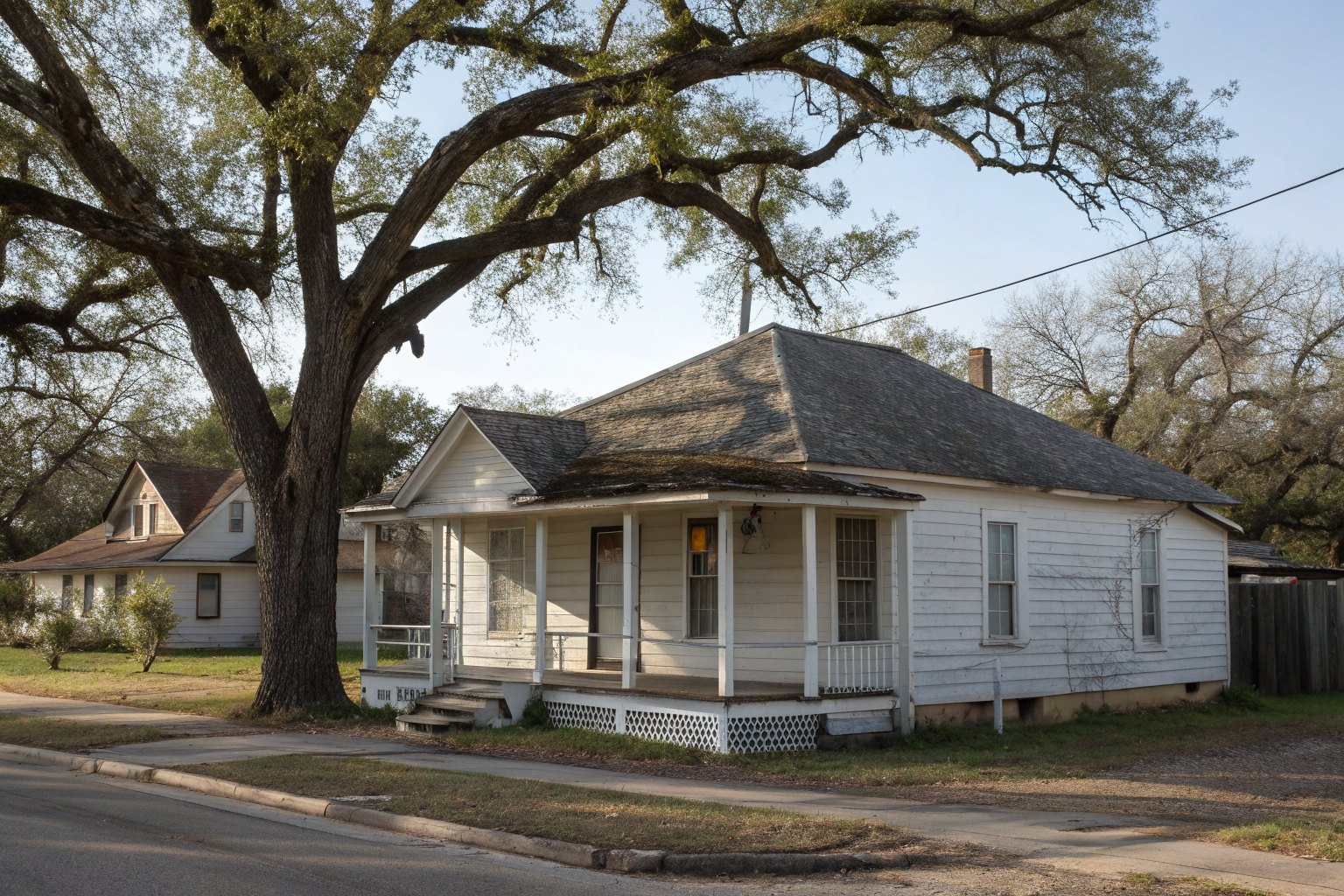 An older one-story wood frame house with a porch and a worn shingle roof